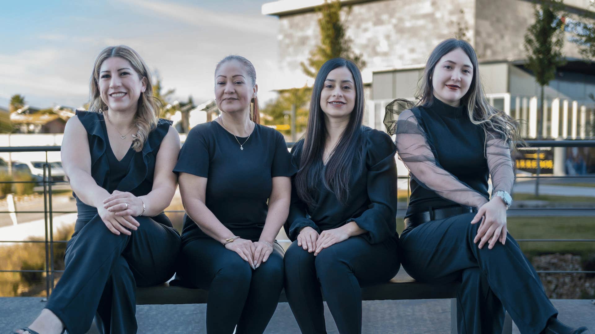 four confident women sitting on bench