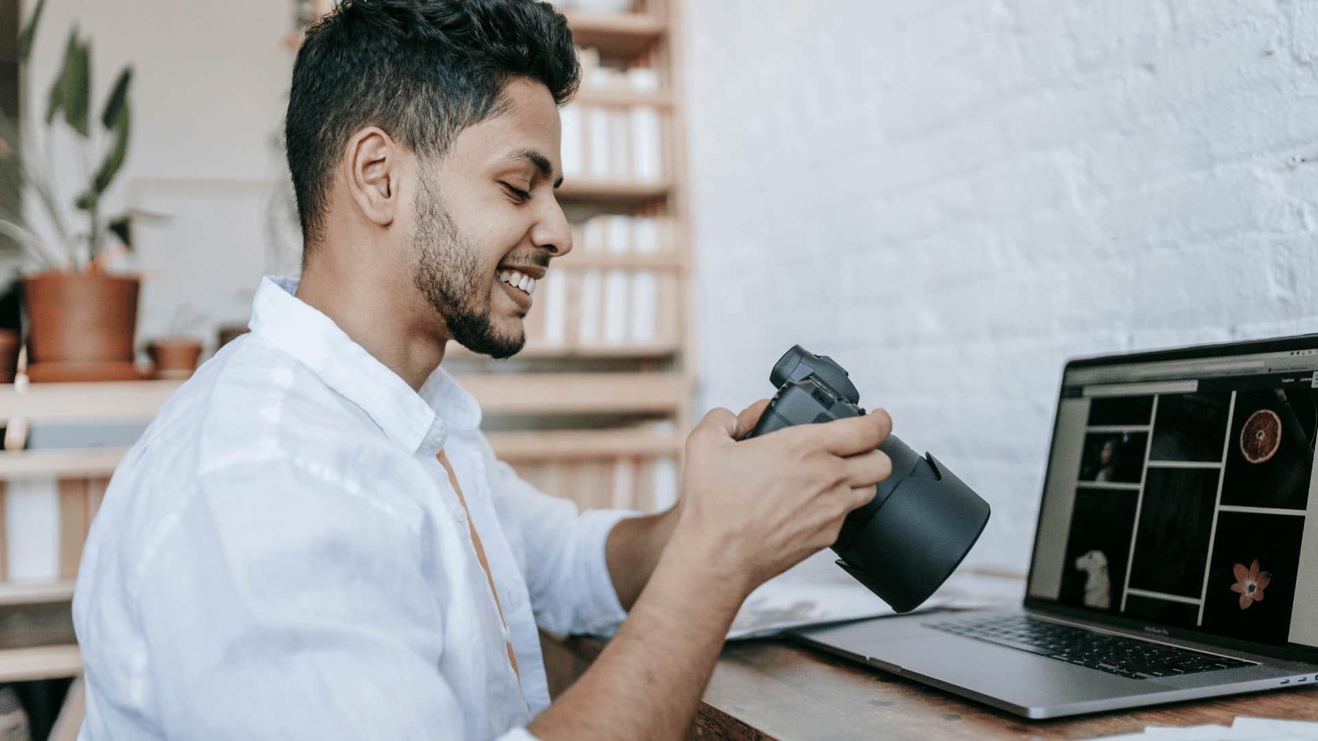 man smiling at camera with photos on laptop