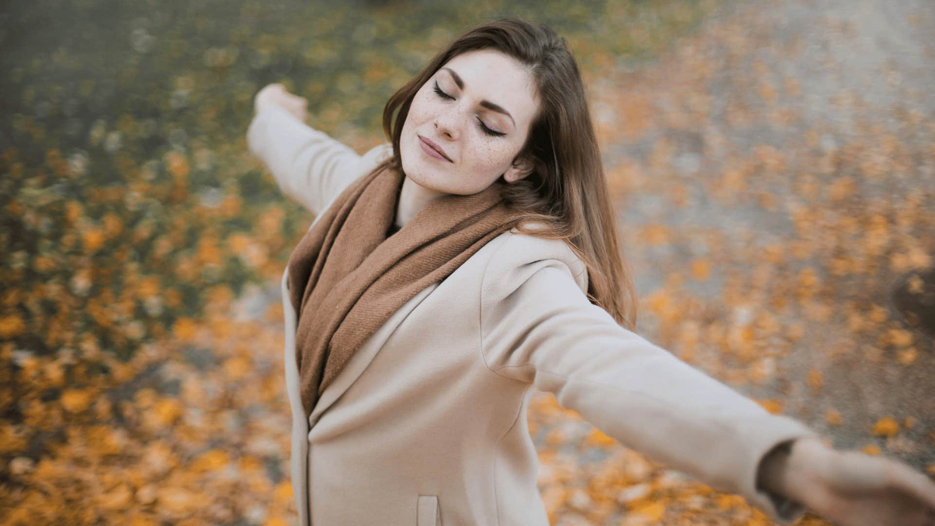 peaceful woman with arms spread out in fall clothes