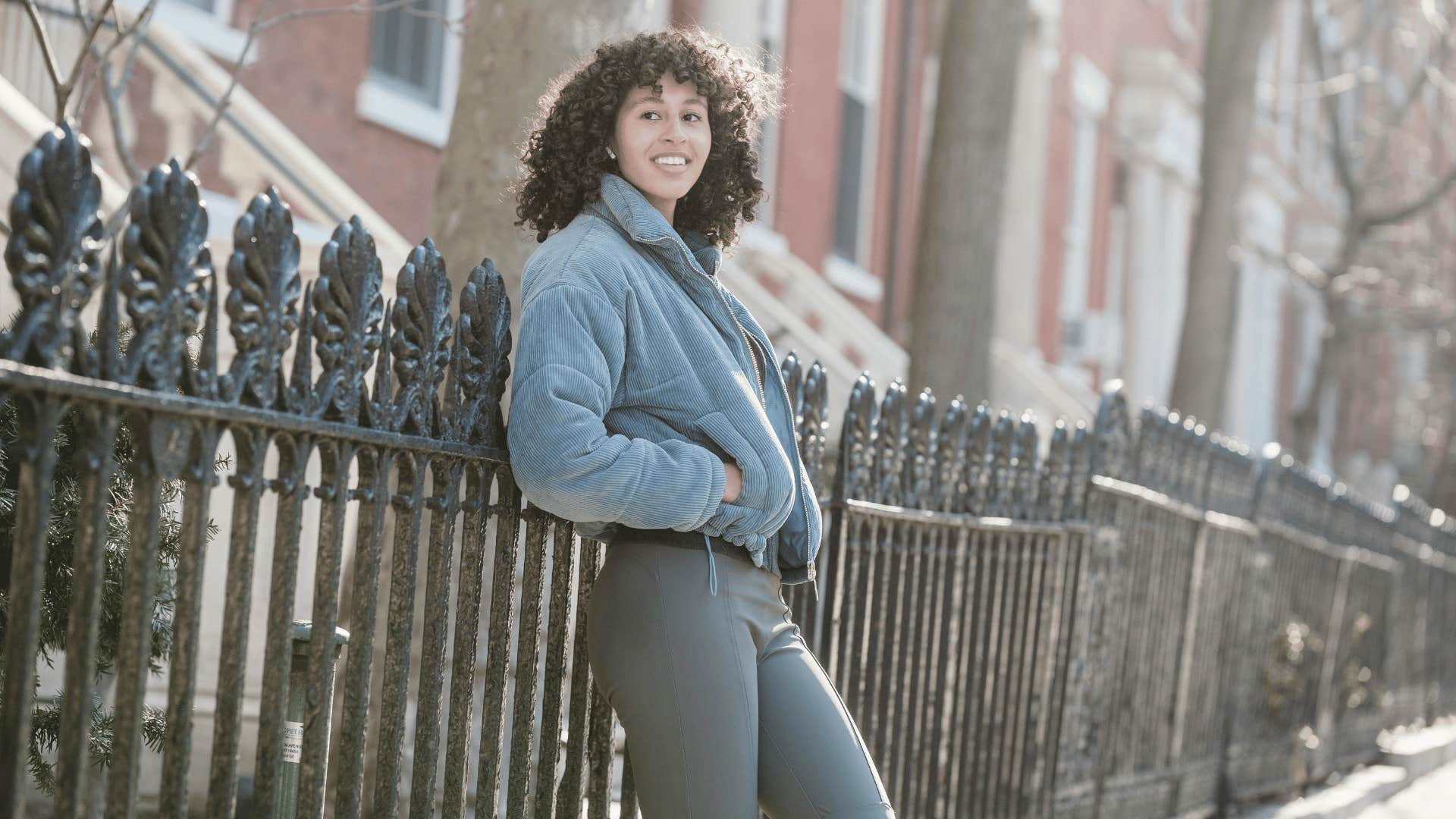 smiling woman leaning against fence