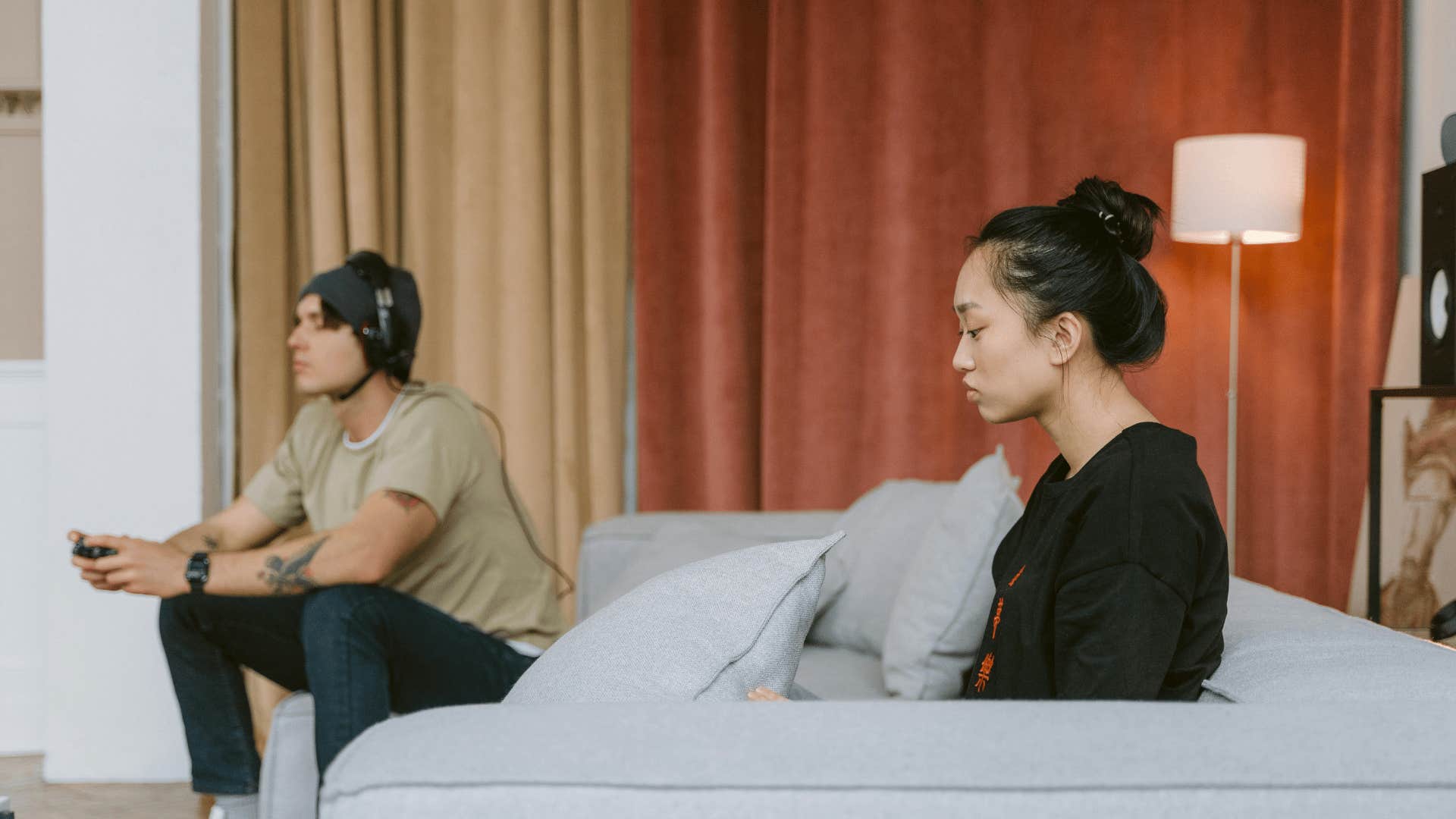 man playing video games next to sad woman