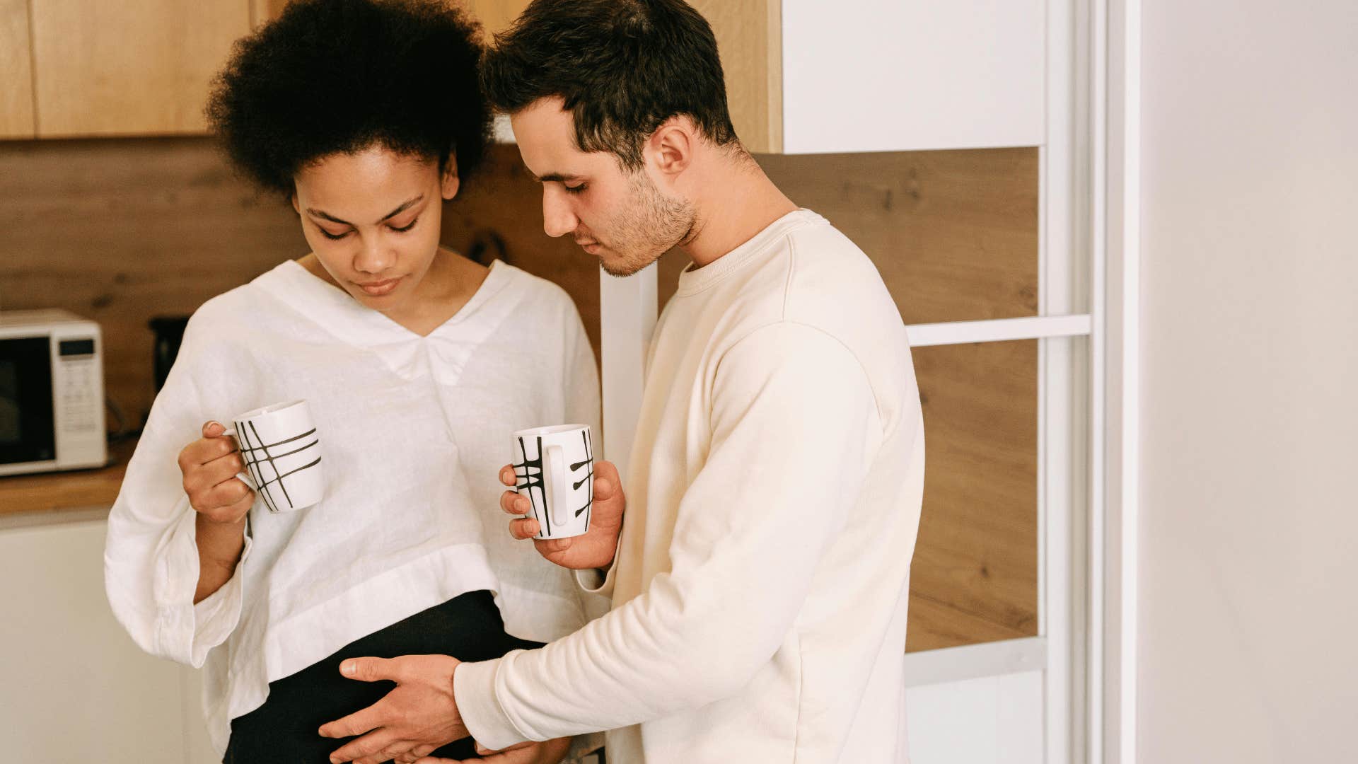 man's palm on woman's pregnant belly