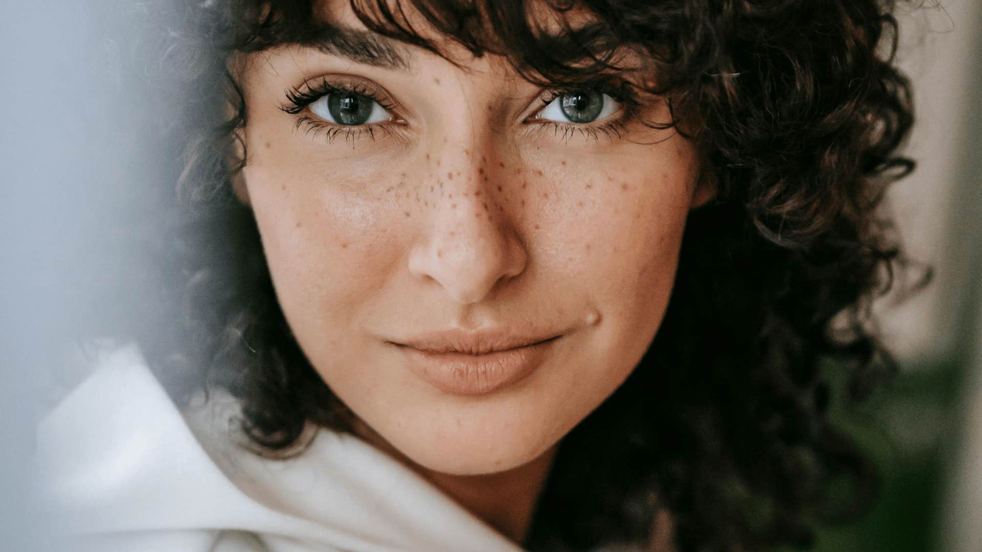 woman with freckles smiling softly