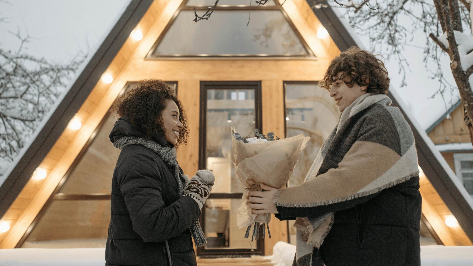 man giving flowers to smiling woman