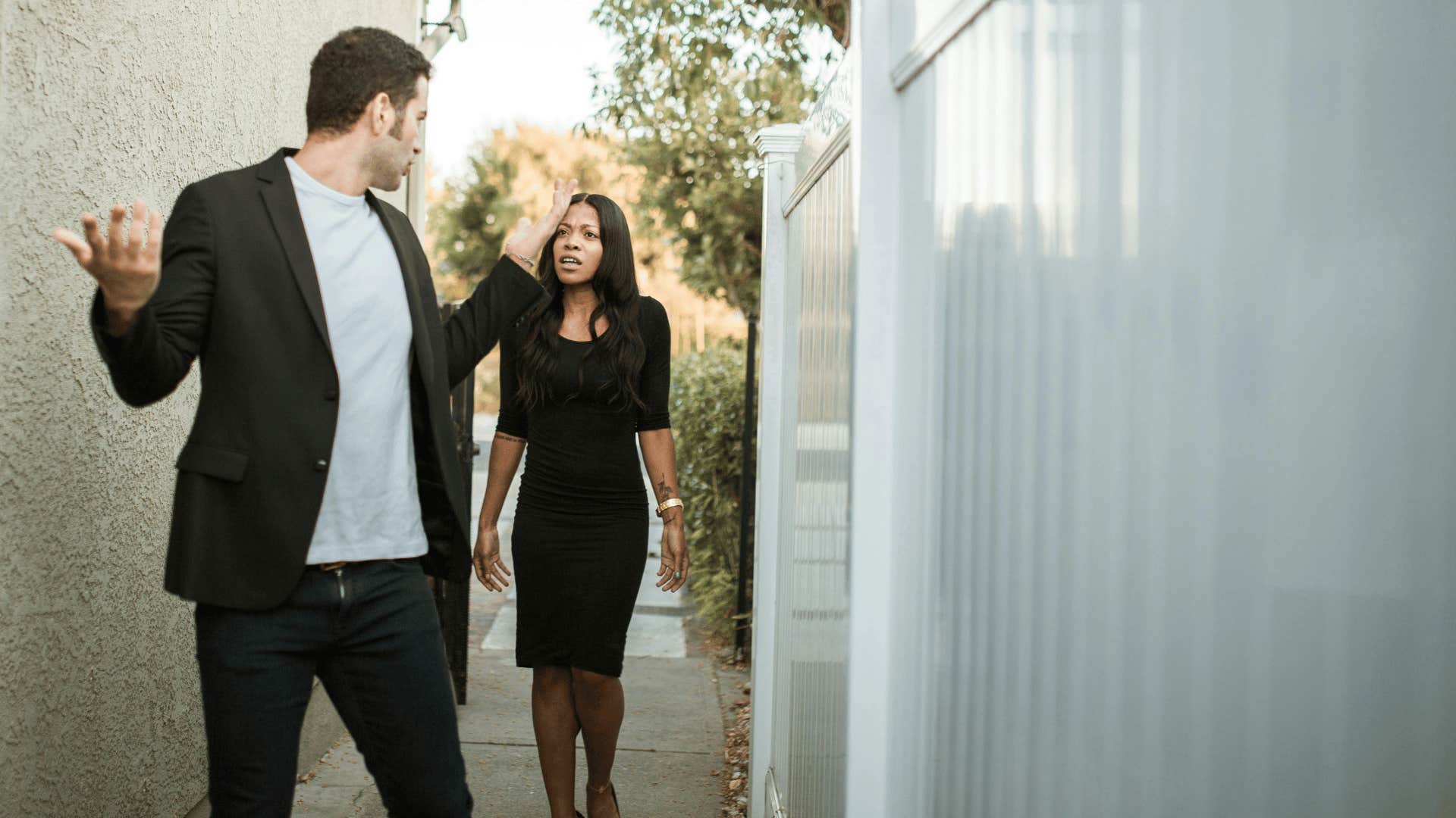 man with hands in the air walking away from upset woman