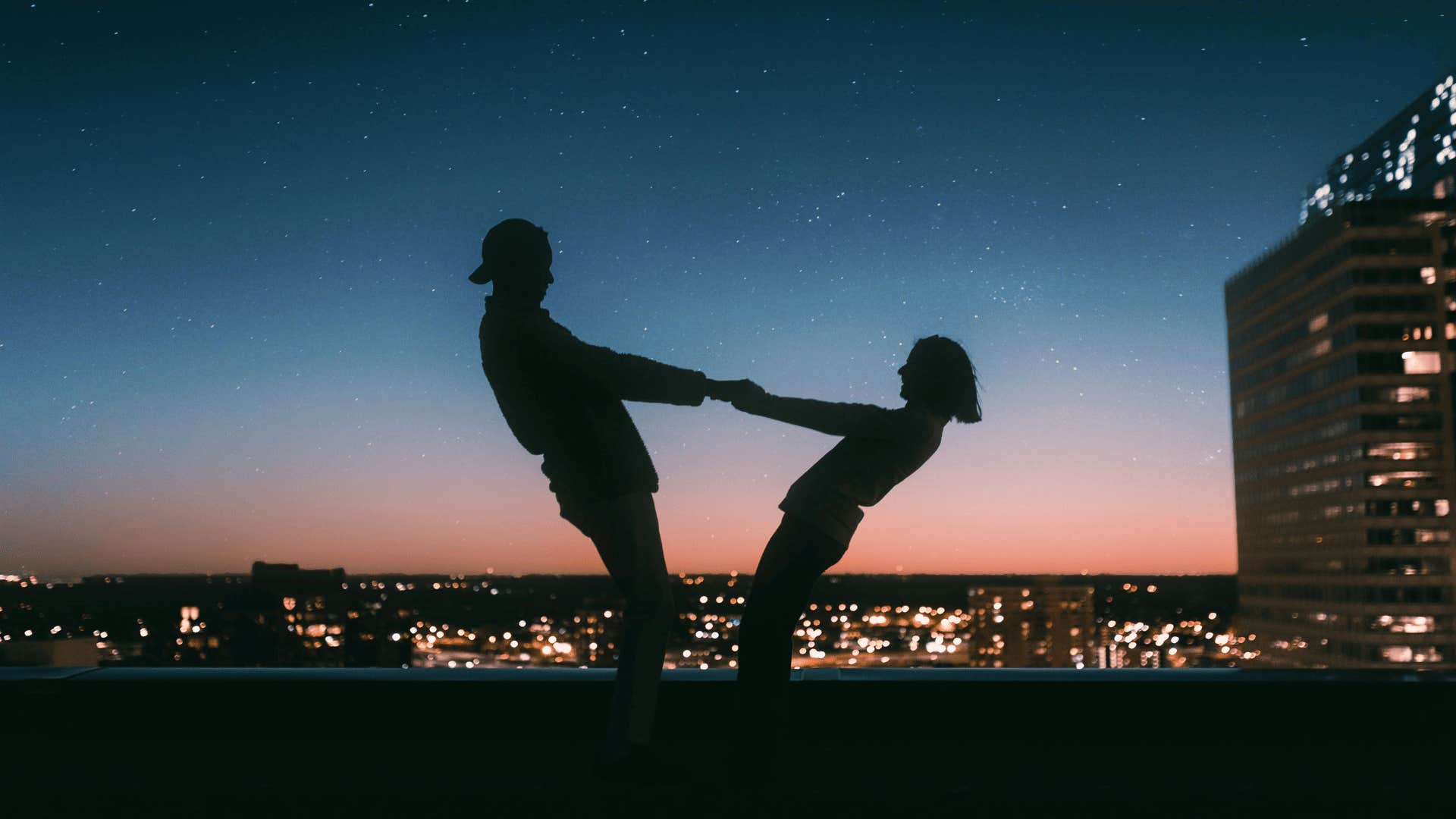 couple holding hands against sunset sky