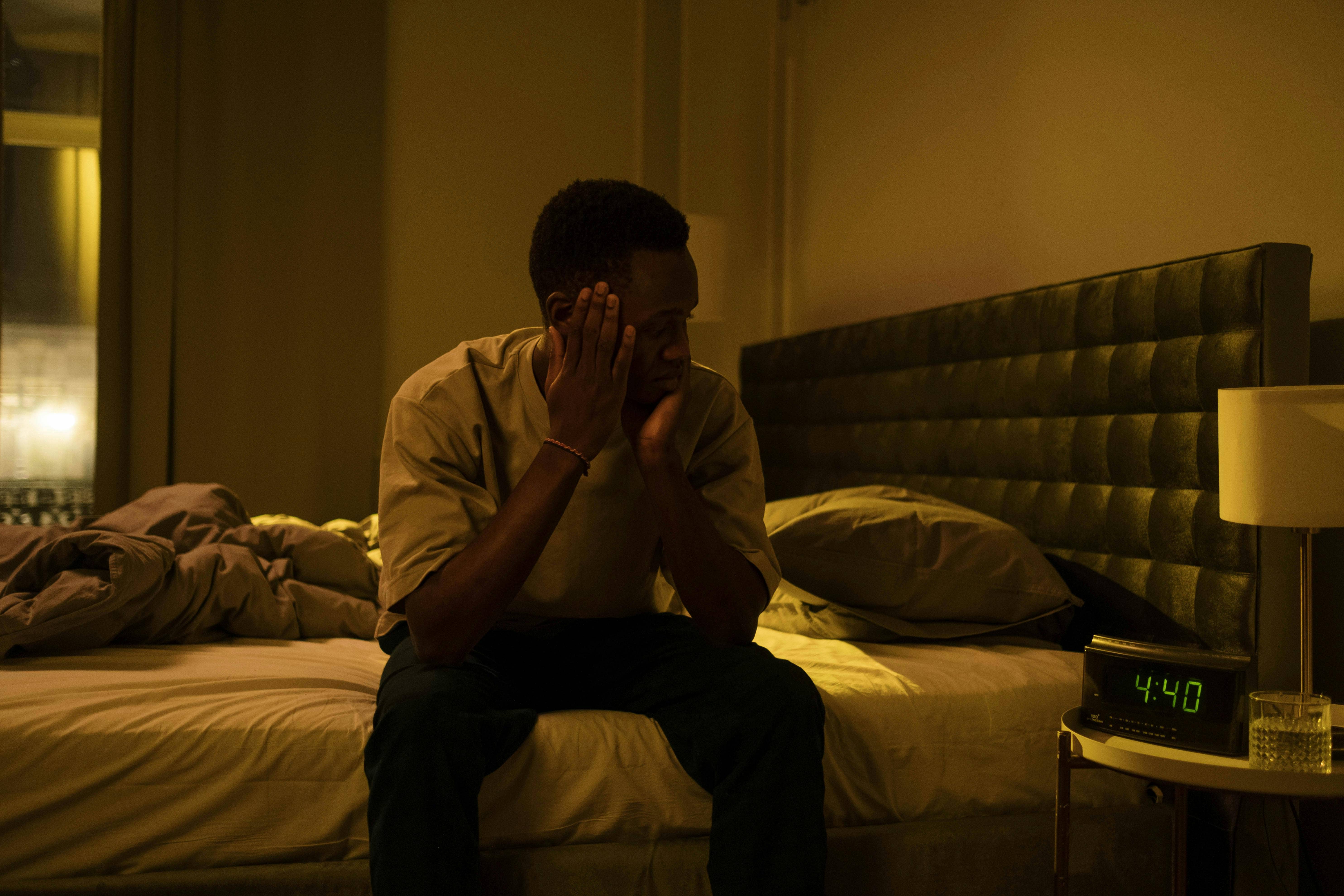 man sitting on bed looking at clock