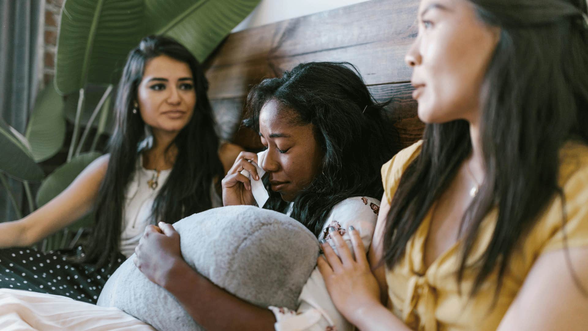 crying woman in between her two friends