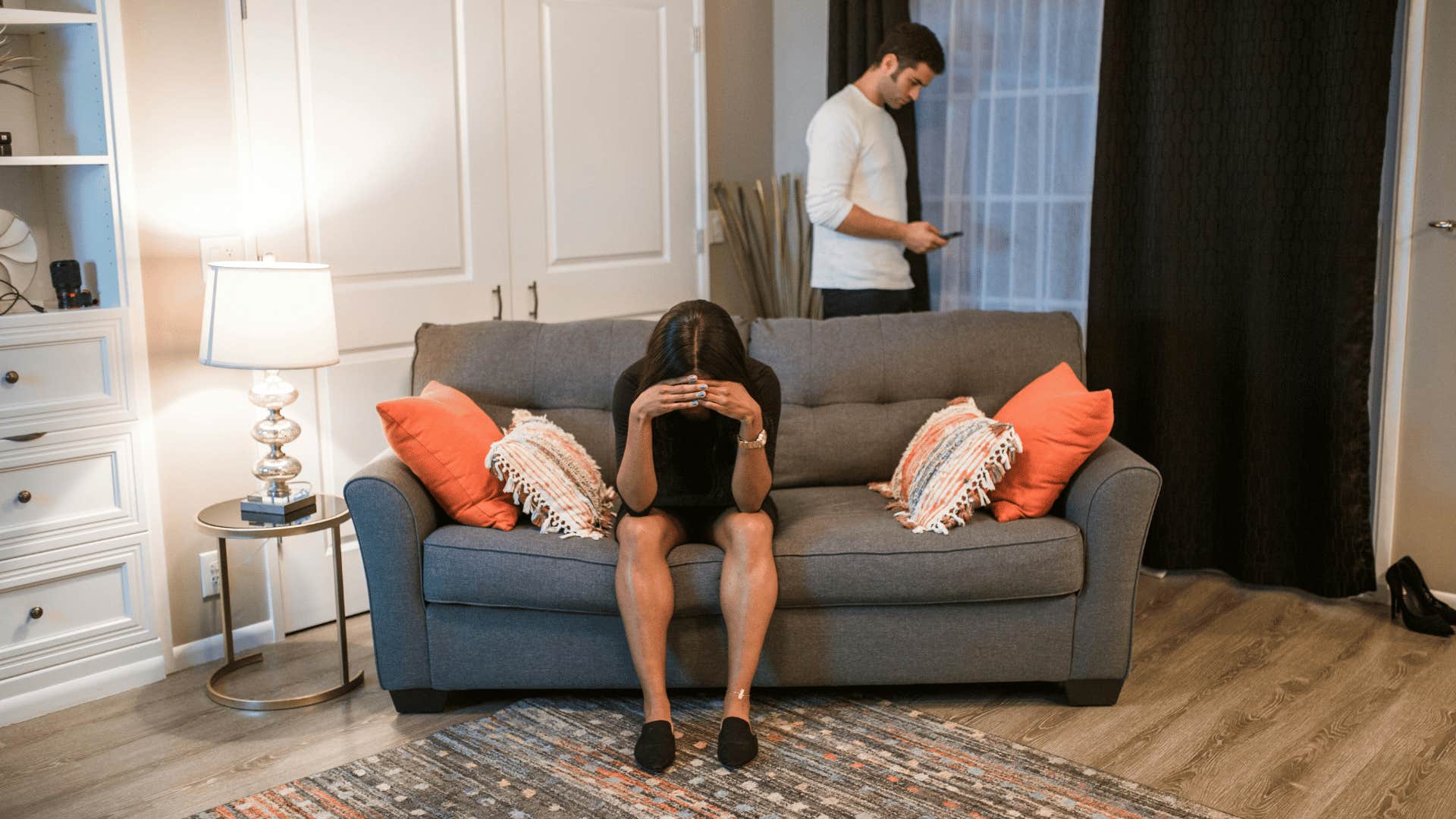 upset woman on couch with calm man on phone