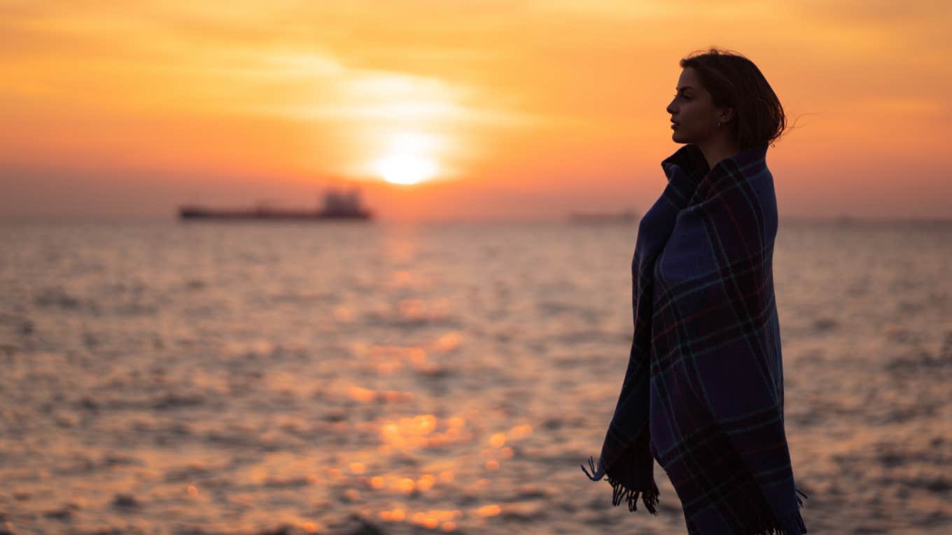 pensive introspective woman reflects while watching sunset at the beach