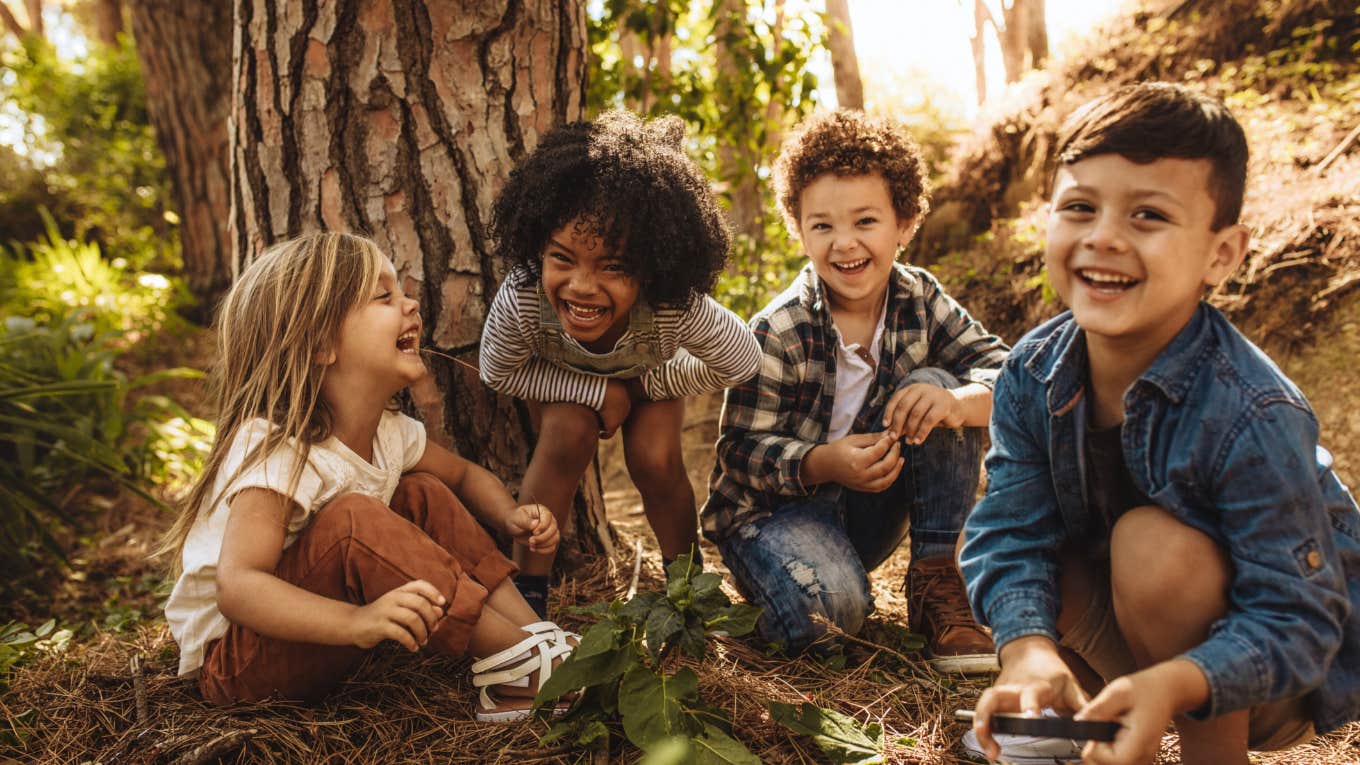 group of laughing kids playing and exploring in forest 