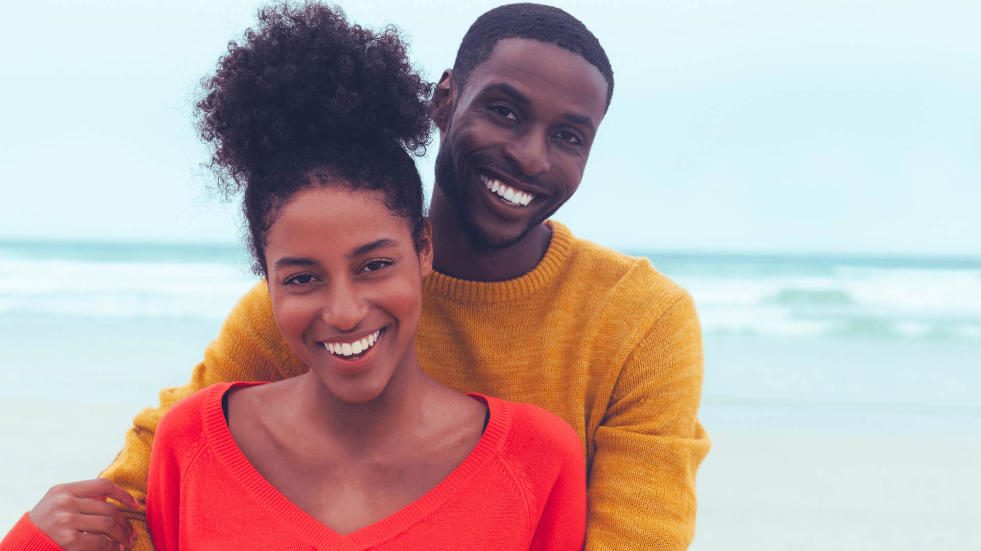 Couple happy together near the ocean wearing bright colors