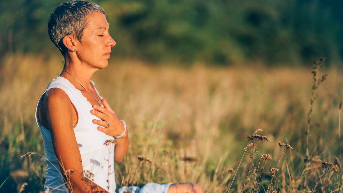 woman meditating and manifesting in a field outside