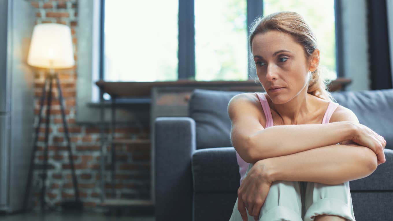 grieving woman arms crossed over legs at home 