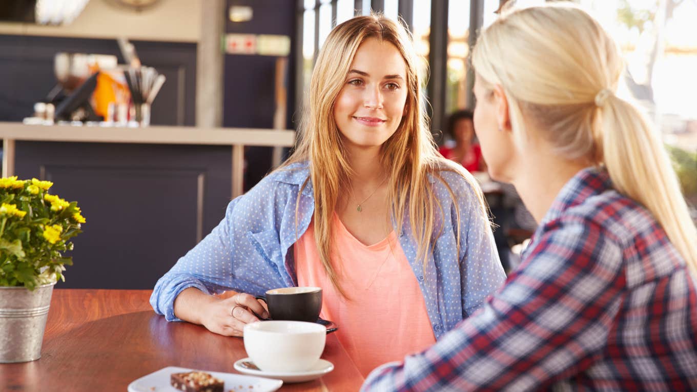 two blonde friends talking over coffee at cafe 