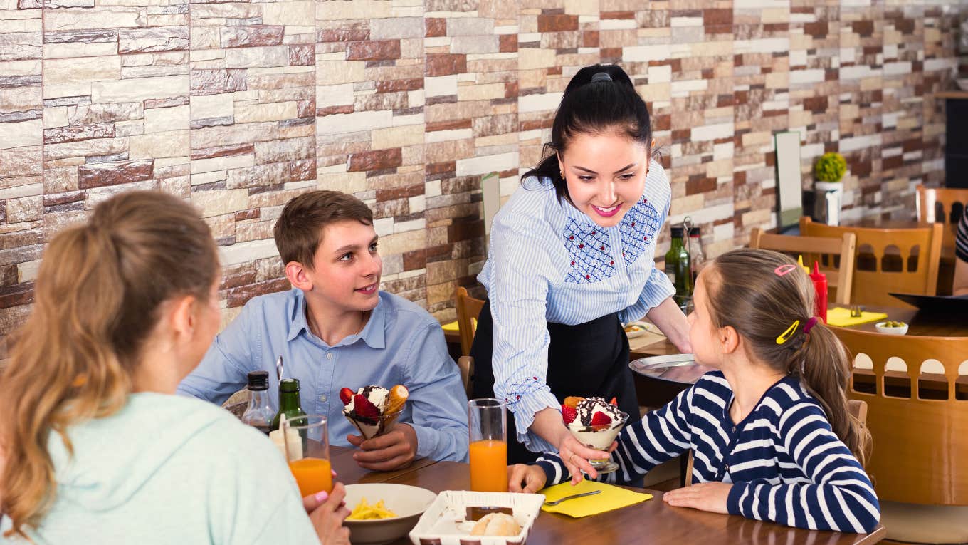 smiling waitress brings kids sundae at restaurant