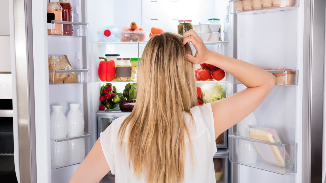 Rear View Of Young Woman Looking In Fridge At Kitchen