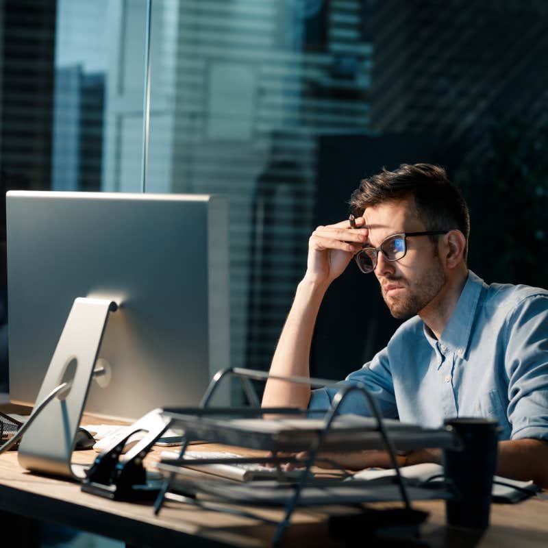 overworked employee sitting in front of computer at desk