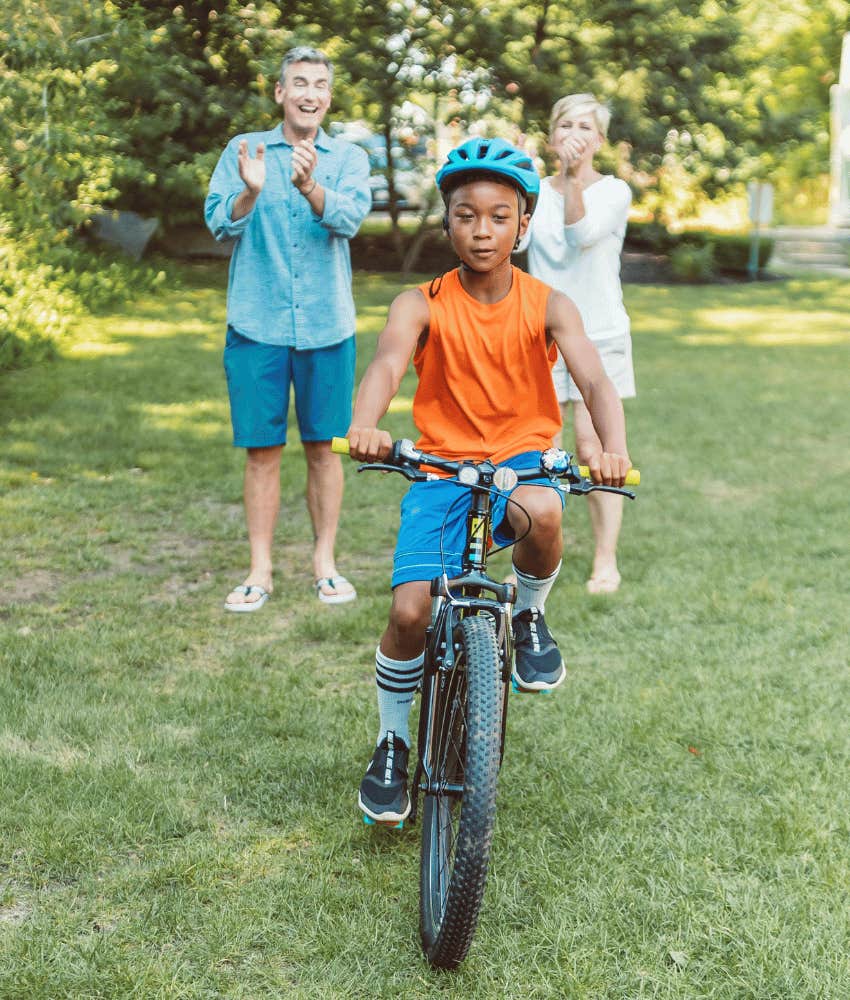 child riding a bike while parents watch