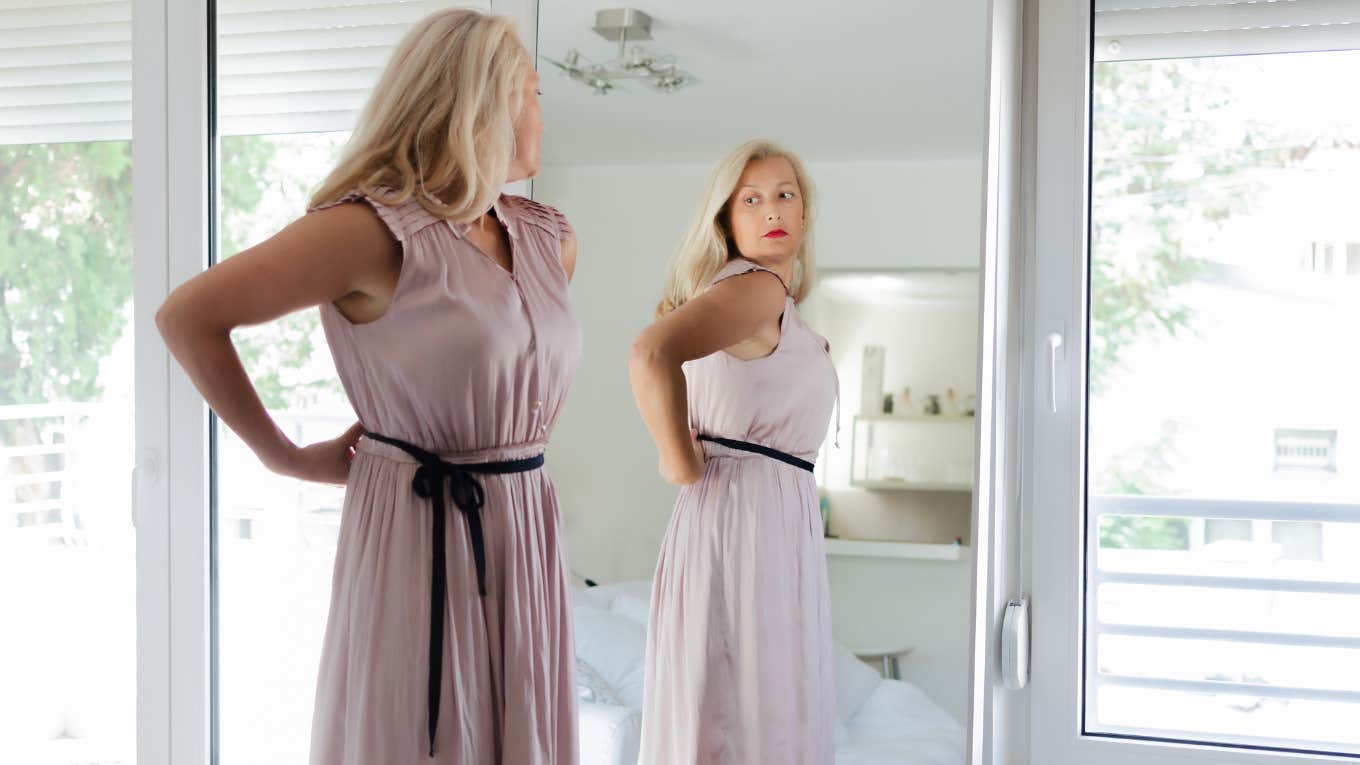 Bridesmaid examining how she looks in her pink dress in a mirror