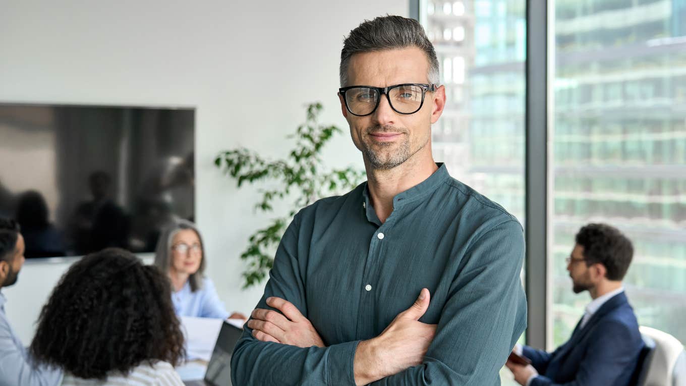 CEO standing in meeting room with arms crossed 