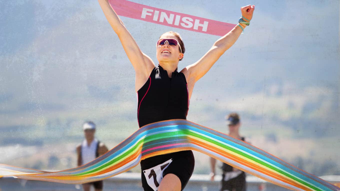 Woman crossing triathlon finish line after battling sexuality and chronic pain