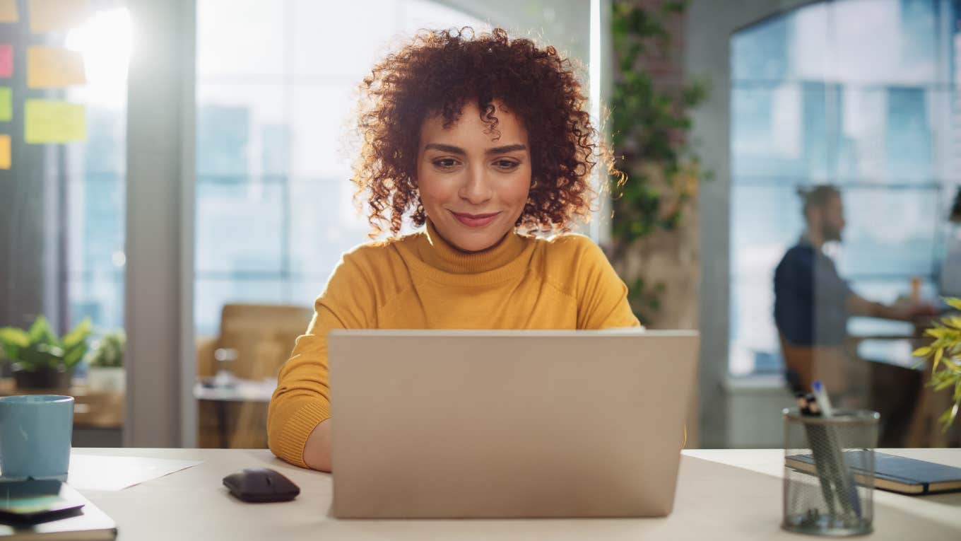 Employee working happily at her computer in an office