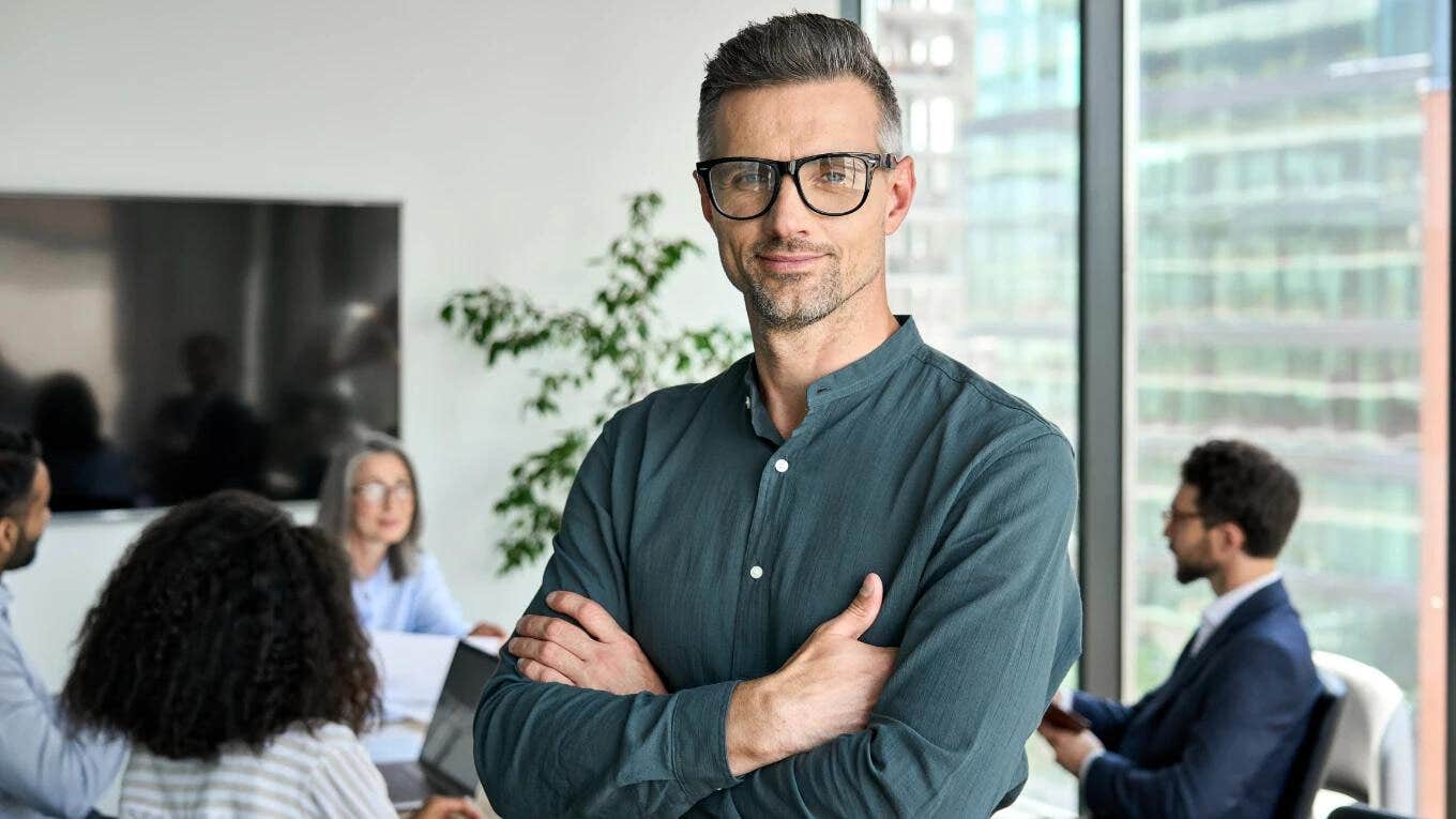 boss with his arms crossed with employees behind him