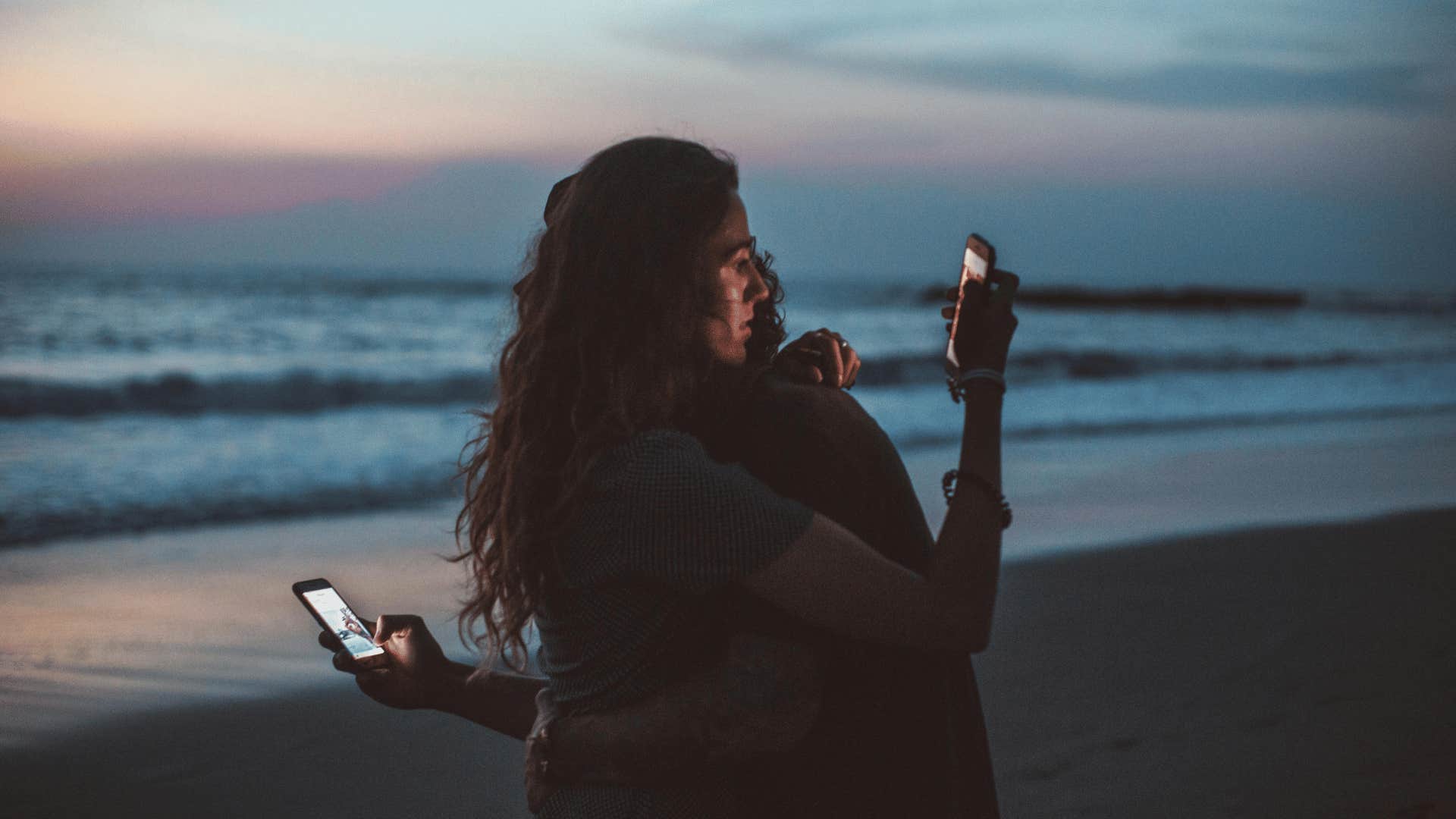 couple hugging while on social media behind each other's backs