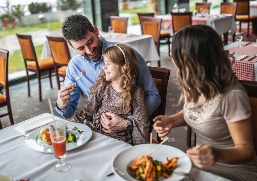 family eating together at restaurant dad feeding daughter