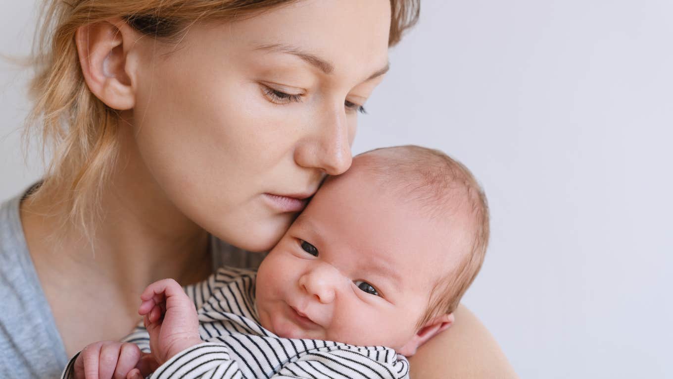 Sad mom snuggling infant daughter 