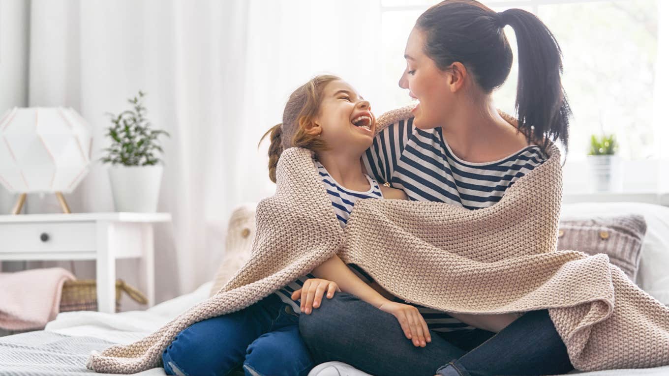 woman with little girl sharing blanket on bed