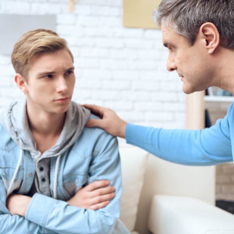 father with hand on teen son's shoulder speaking to him