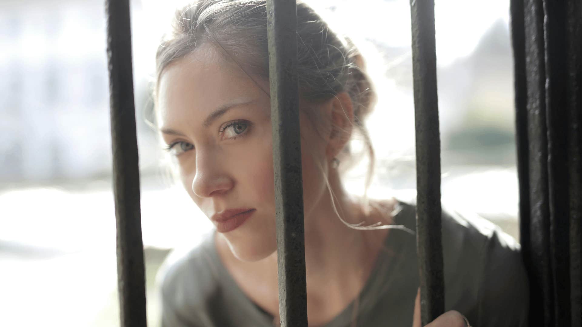 calm woman looking through bars