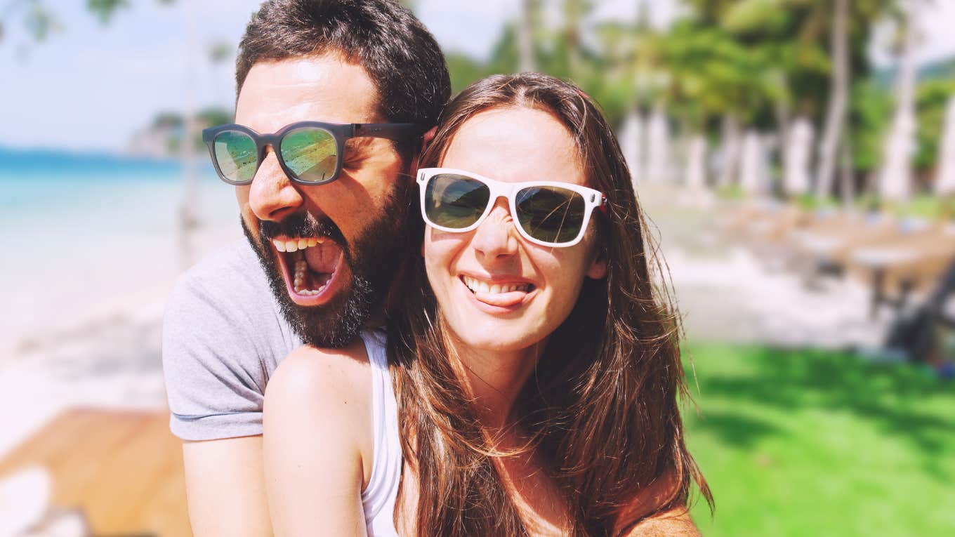 Happy couple by a beach, doesn't realize the damage in their relationship