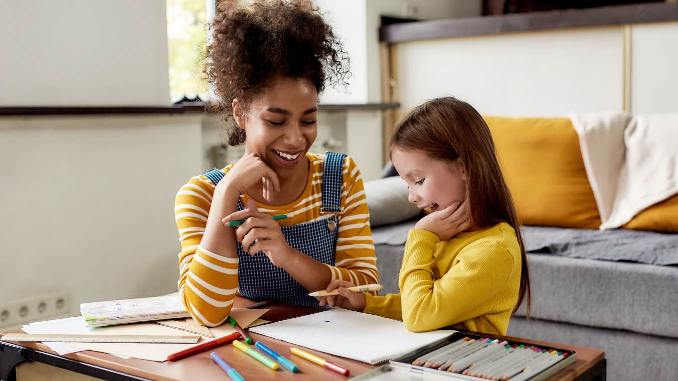 Babysitter sitting with young girl at a table. 