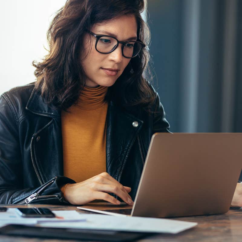 woman with glasses working on laptop