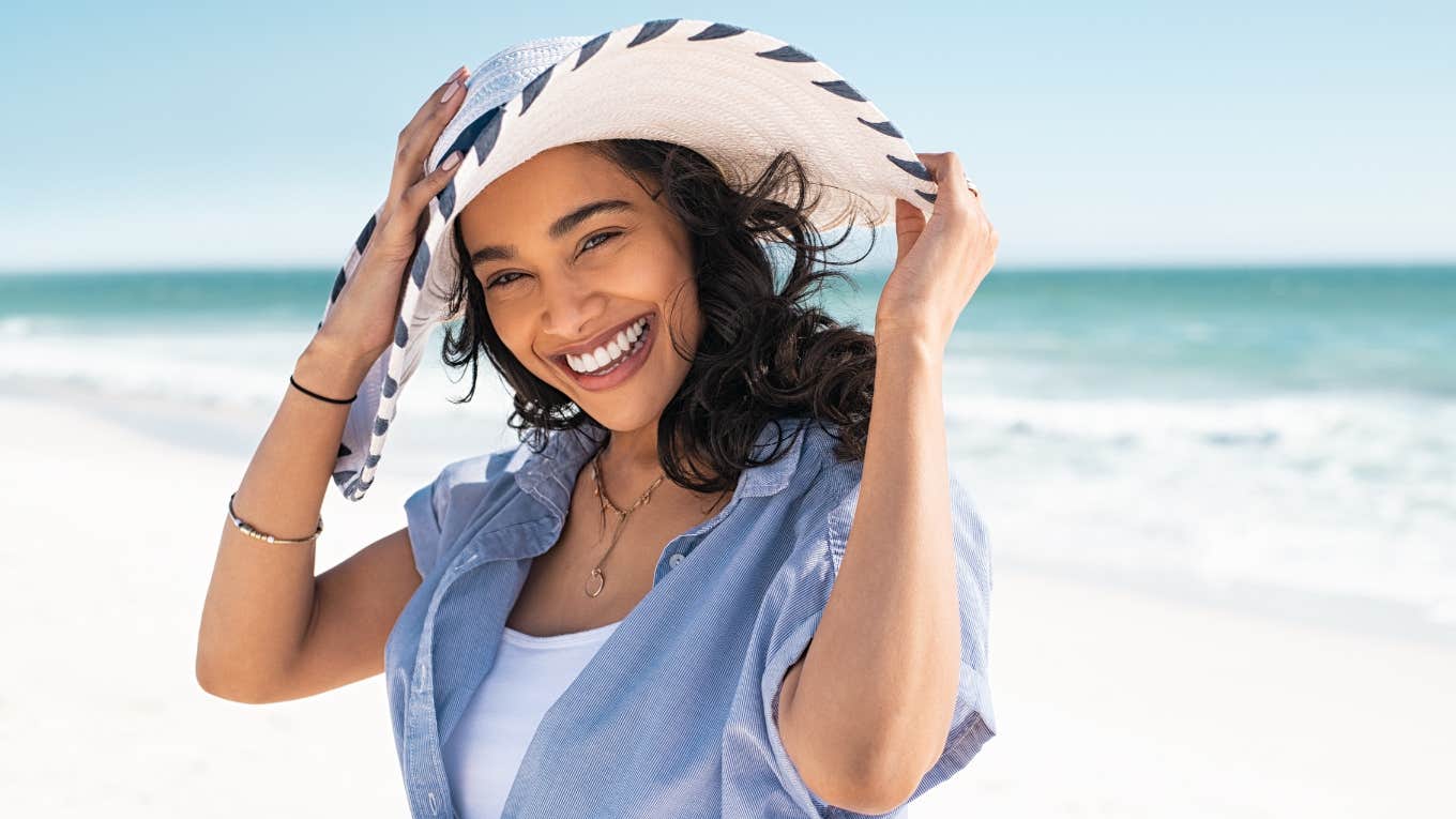 Smiling woman wearing sun hat on the beach