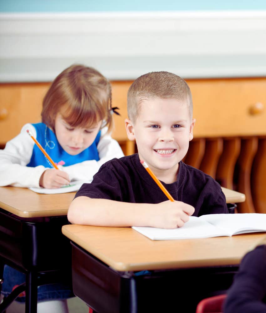 first grader smiling while sitting at a desk in his classroom