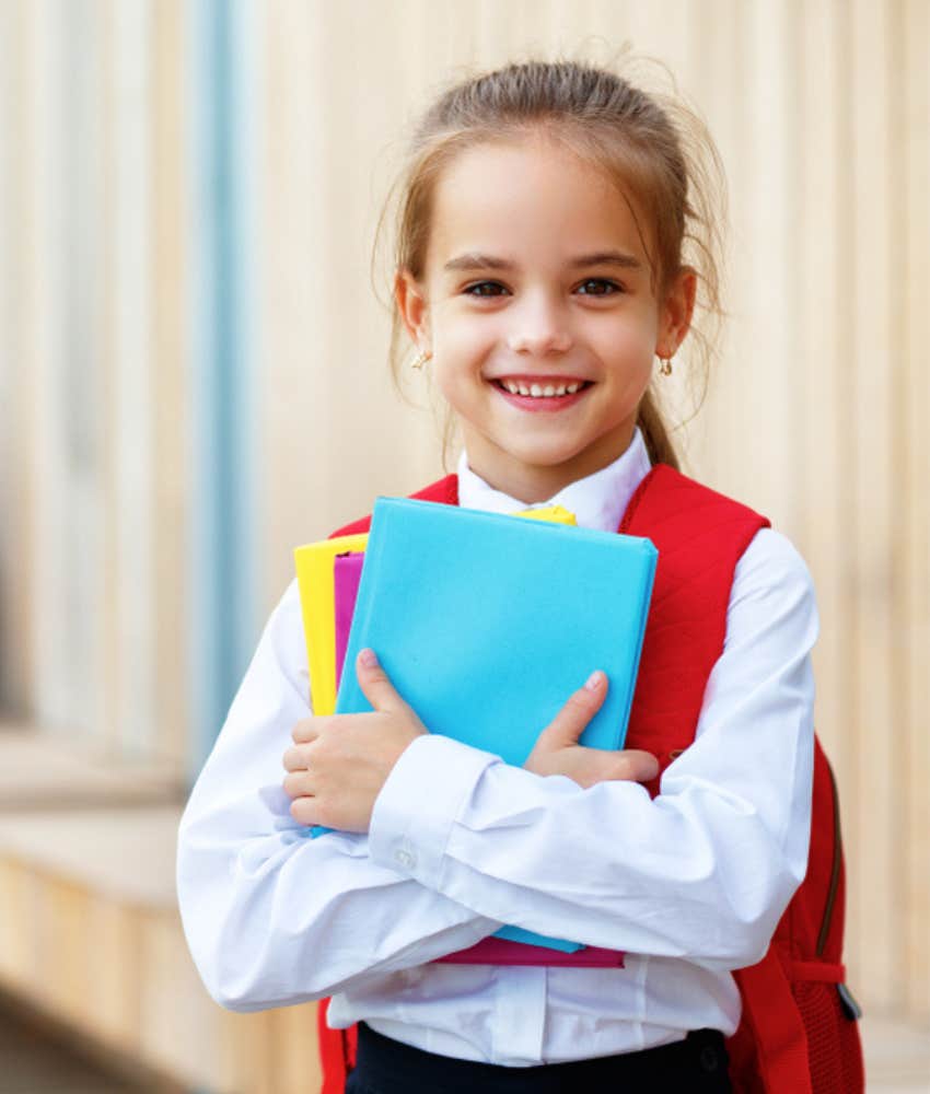 smiling first grader holding folders