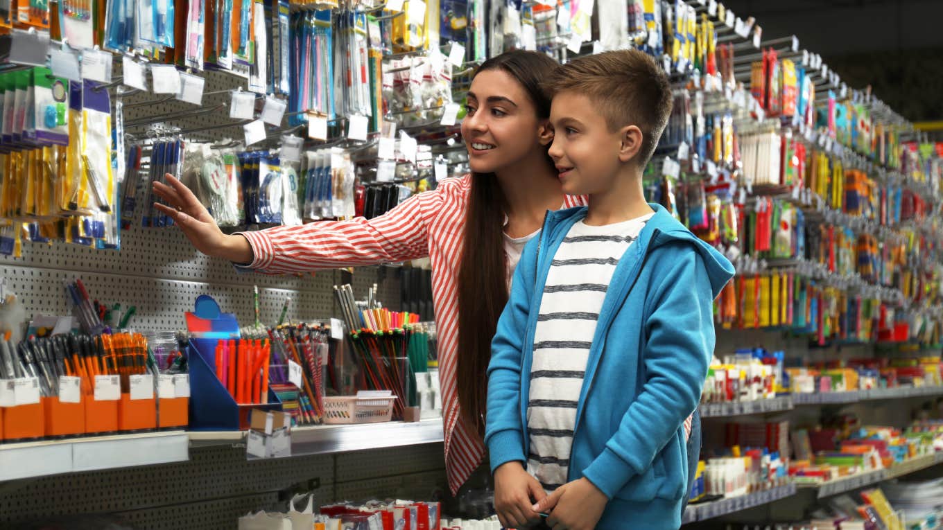 Little boy with mother choosing school stationery in supermarket