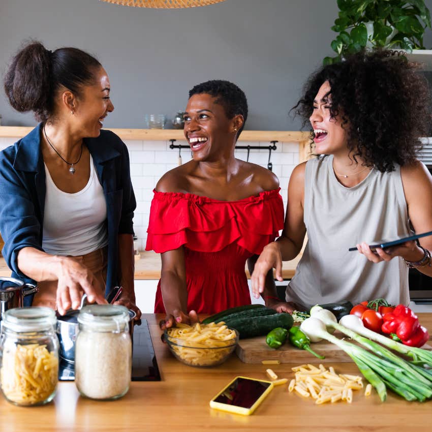 Women secretly competing together happily talking in kitchen. 