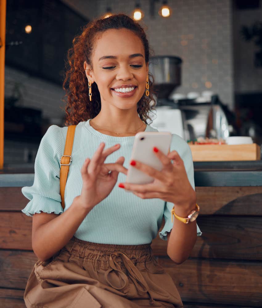 Gen Z woman smiling looking at phone