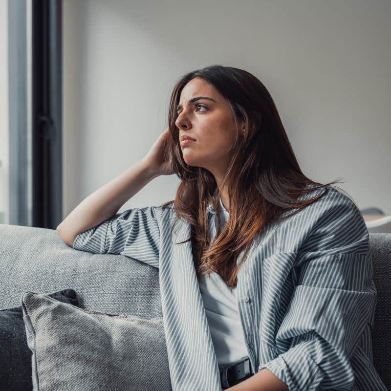 lonely woman sitting on couch staring out window