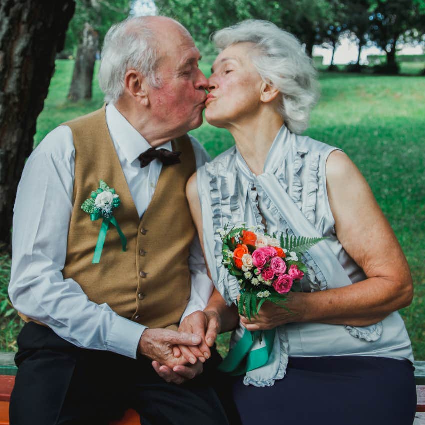 Grandparents hugging and kissing each other like newlyweds.