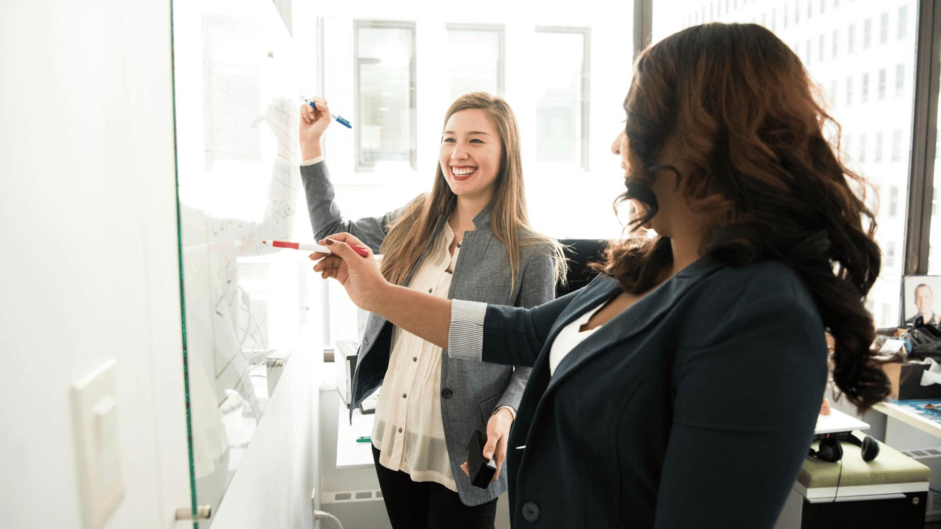 two women writing stuff done on whiteboard