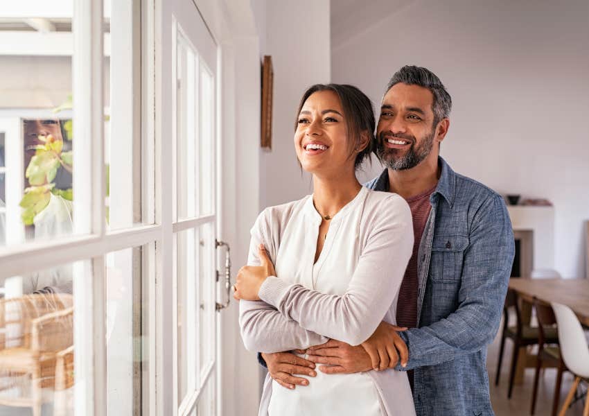 happy couple embracing each other smiling in entryway of home