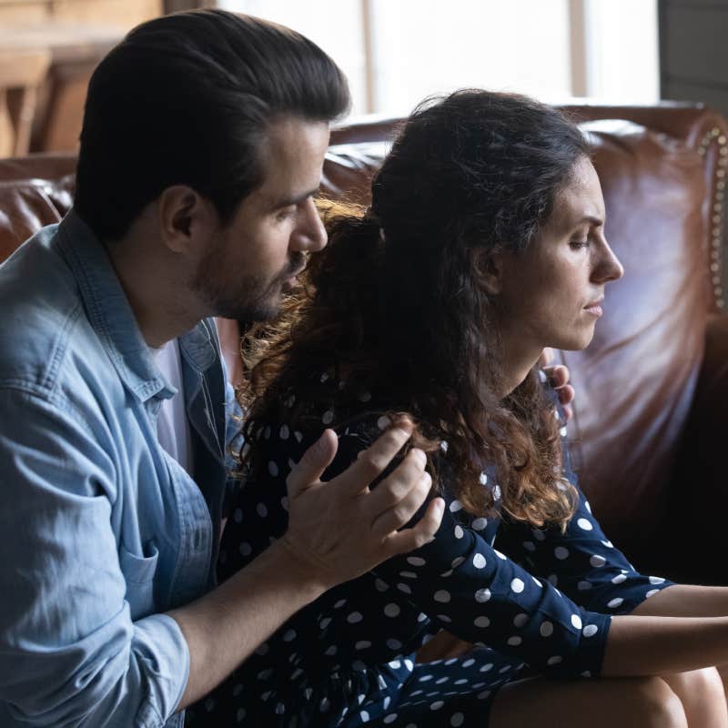 husband comforting upset wife on couch