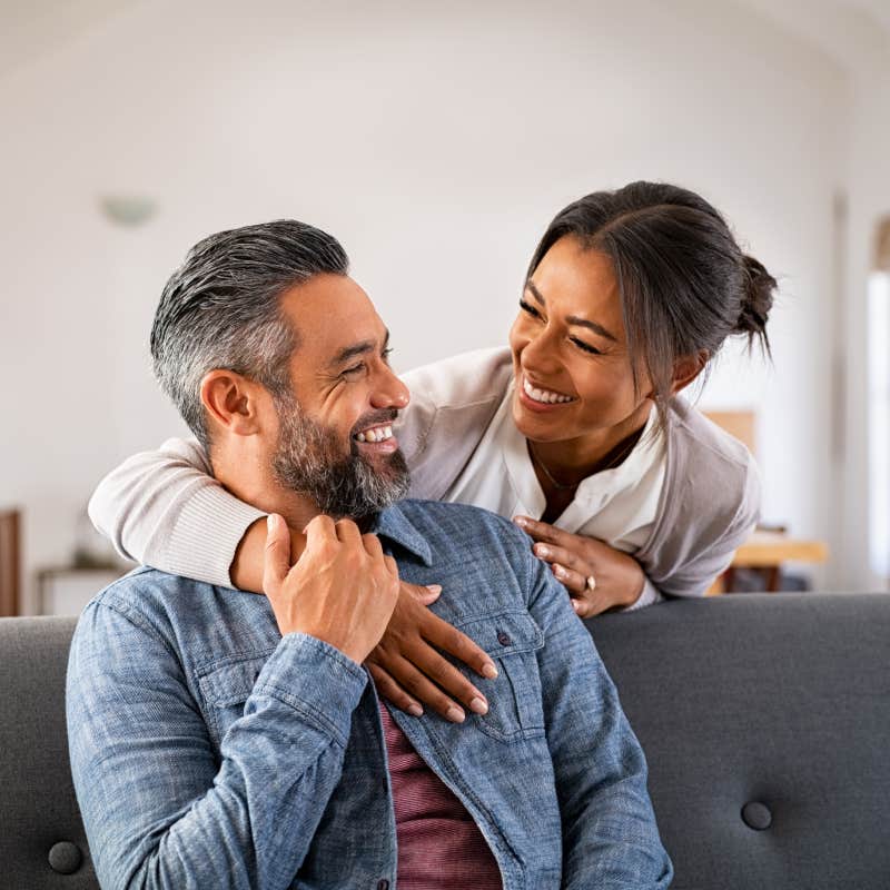 woman hugging her husband on the couch from behind in the living room