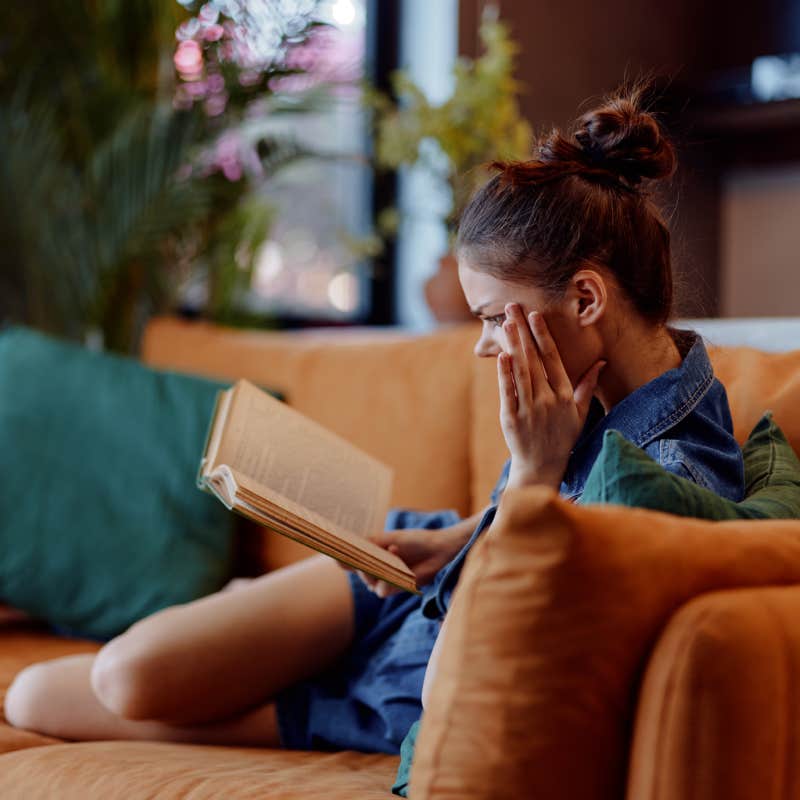 woman reading book on couch